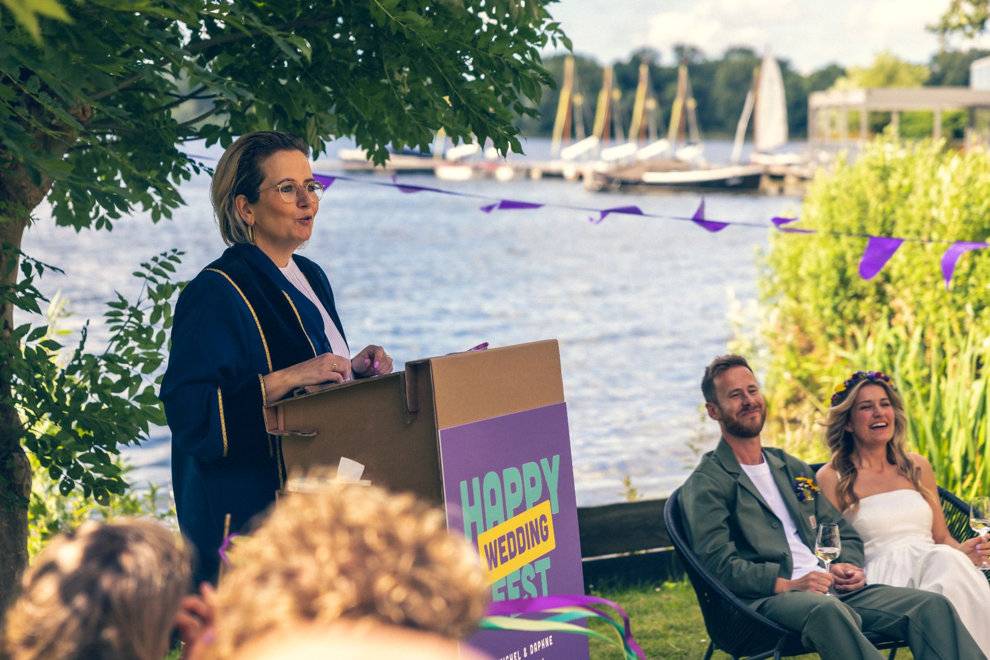 Marjolein spreekt een bruidspaar toe tijdens een ceremonie aan het water
