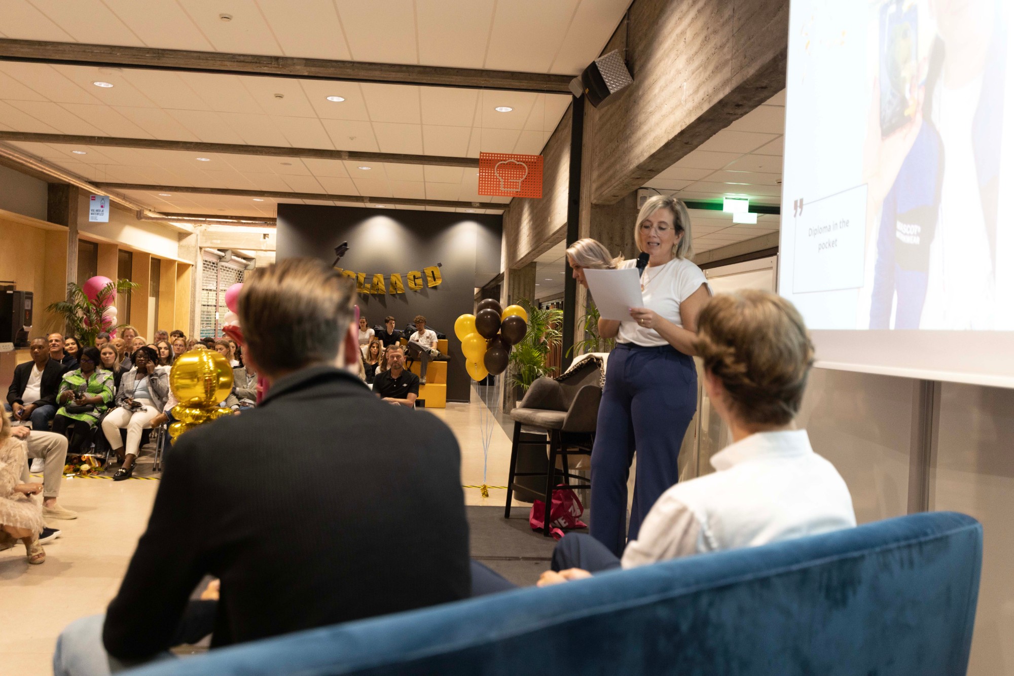 Marjolein aan het woord met een microfoon tijdens een evenement